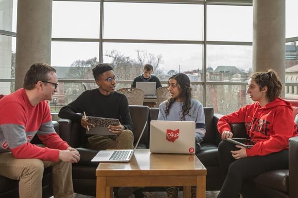 Four students huddle and talk in the Ohio Union