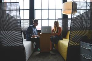 An advisor sits with a student in a lounge